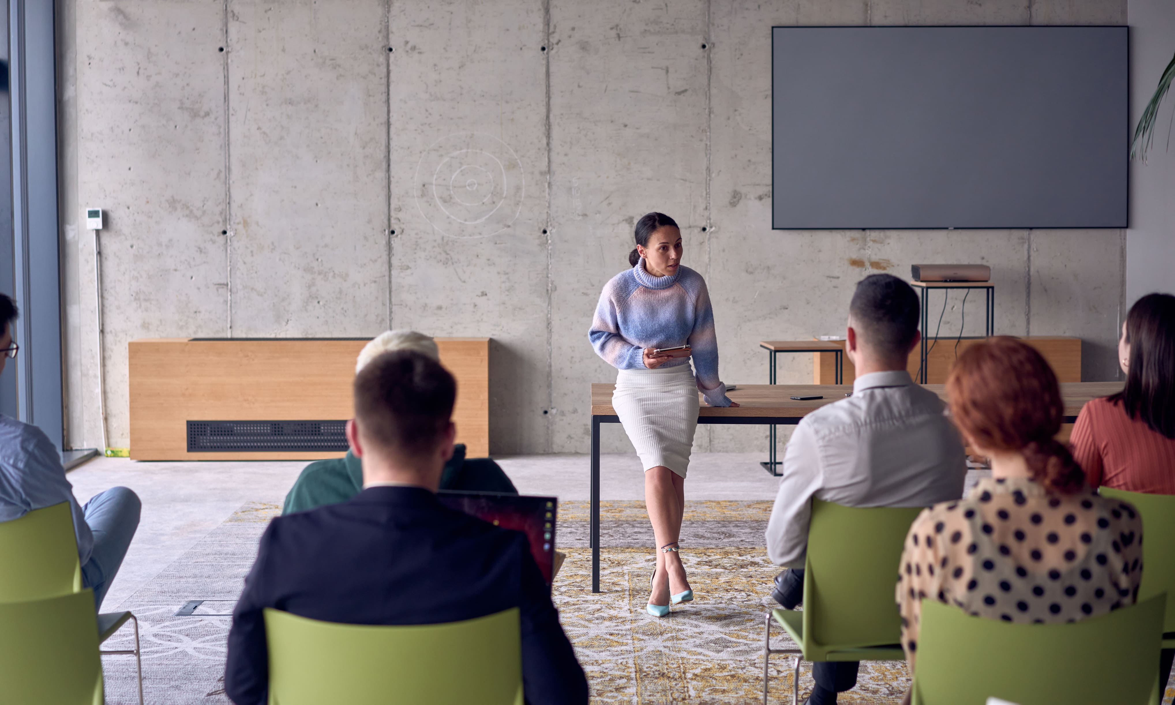 Síndica conduzindo reunião com condôminos em auditório moderno, simbolizando a escuta ativa e o planejamento coletivo como parte da gestão preventiva.